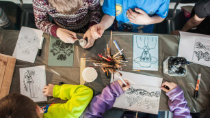 Warsztaty plastyczne - zdjęcie z góry stołu, przy którym dzieci tworzą rysunki
